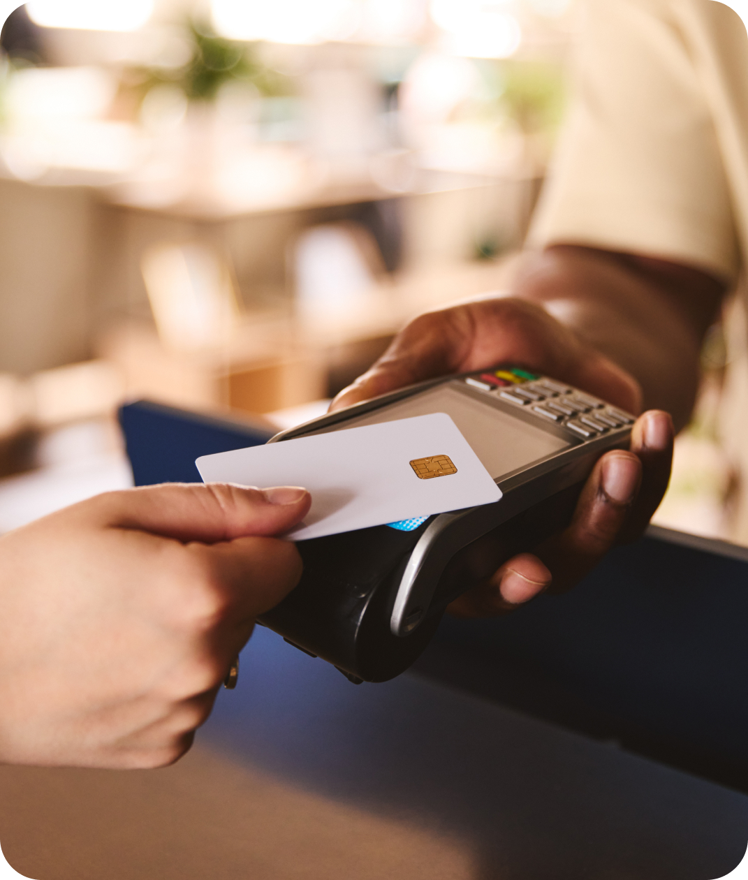 A hand holding a card taps a payment machine